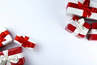 Parlak ipek fiyonkla bağlanmış kırmızı ve beyaz kağıda sarılmış bir sürü Noel hediyesi. Kırmızı ve beyaz ambalajlı birçok yeni yıl hediyesi. Üst görünüm, kapat, boşluğu kopyala, arkaplan, düzleştir.