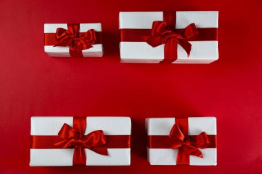 Parlak ipek fiyonkla bağlanmış kırmızı ve beyaz kağıda sarılmış bir sürü Noel hediyesi. Kırmızı ve beyaz ambalajlı birçok yeni yıl hediyesi. Üst görünüm, kapat, boşluğu kopyala, arkaplan, düzleştir.