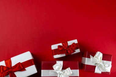 Parlak ipek fiyonkla bağlanmış kırmızı ve beyaz kağıda sarılmış bir sürü Noel hediyesi. Kırmızı ve beyaz ambalajlı birçok yeni yıl hediyesi. Üst görünüm, kapat, boşluğu kopyala, arkaplan, düzleştir.