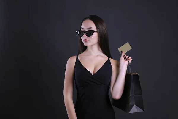 Νεαρή γυναίκα ντυμένη στα μαύρα ποζάροντας με τσάντα για ψώνια. — Φωτογραφία Αρχείου