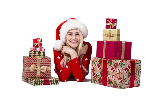 Ritratto di giovane donna bionda vestita con maglione rosso a maglia seduta tra due pile di regali natalizi in carta da regalo festiva. Sfondo bianco, spazio di copia . — Foto Stock