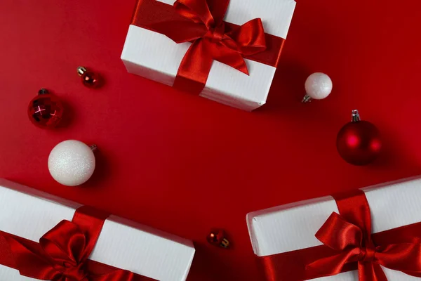 Hromada vánočních dárků zabalených do červeného a bílého papíru svázaných lesklou hedvábnou mašlí. Několik nových let dárky v červeném a bílém obalu. Horní pohled, zavřít, kopírovat prostor, pozadí, byt ležel. — Stock fotografie
