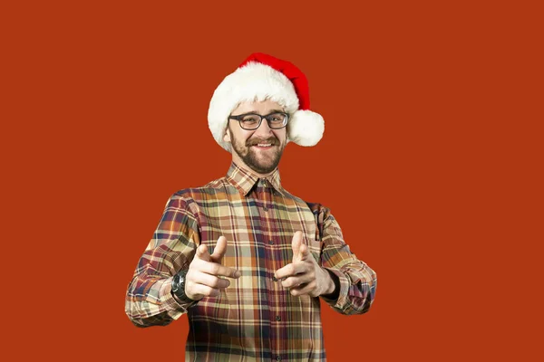 戴着圣诞老人帽子和眼镜的帅哥圣诞老人指着白色墙壁的一侧。圣诞节的概念。模拟, 复制文本的空间。希普斯特胡须男子思考圣诞节礼物想法 — 图库照片