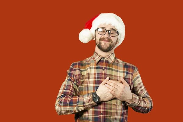 戴着圣诞老人帽子和眼镜的帅哥圣诞老人指着白色墙壁的一侧。圣诞节的概念。模拟, 复制文本的空间。希普斯特胡须男子思考圣诞节礼物想法 — 图库照片