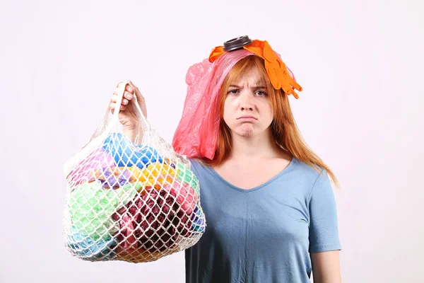 Femme rousse émotionnelle regardant stressé, recouvert de déchets en plastique nocifs pour l'environnement, sacs et pailles de différentes couleurs. Concept zéro déchet. Triste femelle fronçant les sourcils, en colère à cause des déchets . — Photo