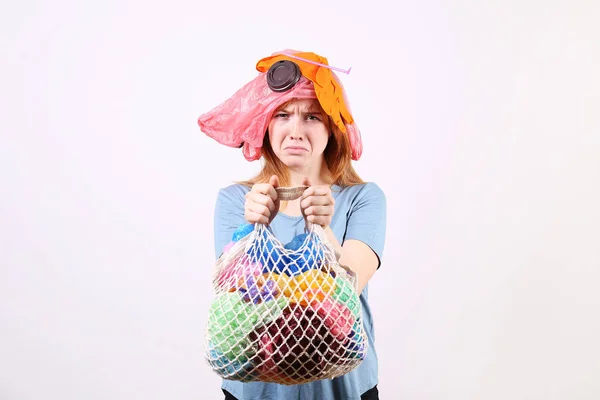 Femme rousse émotionnelle regardant stressé, recouvert de déchets en plastique nocifs pour l'environnement, sacs et pailles de différentes couleurs. Concept zéro déchet. Triste femelle fronçant les sourcils, en colère à cause des déchets . — Photo