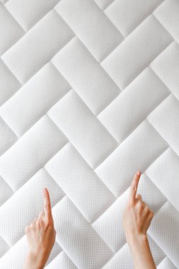 Kadının ellerinin fotokopi alanını gösteren kesikli görüntüsü, beyaz ortopedik yatak desenli arka plan. Hipoalerjenik köpük matress w / uygun spinal alingment ve basınç noktası rahatlama özellikleri. Kapat..