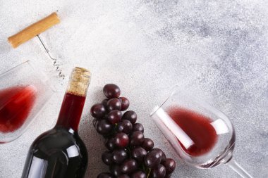Düz kompozisyon, iki kadeh kaliteli kırmızı şarap, bir demet üzüm ve tirbuşon ve grunged beton masa arkaplanı. Pahalı bir şişe Cabernet Sauvignon konsepti. Boşluğu kopyala, üst görünüm.