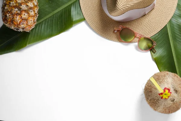 Summer mood concept. Tropical background with ripe organic pinapple, fresh whole coconut with cocktail straw sunglasses and banana palm leaves. Flat lay, top view, close up copy space, isolated.