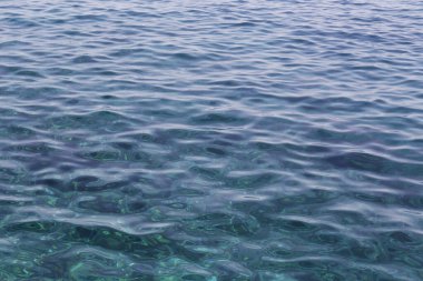 Turkuaz okyanus suyunun ışık yansıma dokusuyla yakın çekimi. Açık deniz, parlak güneş desenleri ve görünür kıçı. Tropik arka plan konsepti. Kapat, metin için boşluk kopyala.