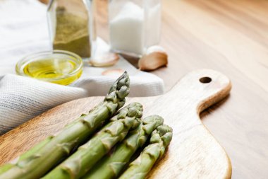 Ahşap dokuma masasında bir sürü çiğ kuşkonmaz var. Yenilebilir kuşkonmaz resmi lahanaları bambu kesme tahtasının üzerine serildi. Kapat, boşluğu kopyala, üst görünüm, düz alan, arkaplan.