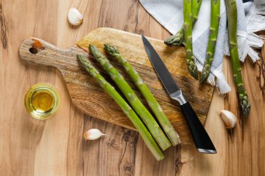 Ahşap dokuma masasında bir sürü çiğ kuşkonmaz var. Yenilebilir kuşkonmaz resmi lahanaları bambu kesme tahtasının üzerine serildi. Kapat, boşluğu kopyala, üst görünüm, düz alan, arkaplan.