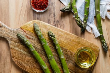 Ahşap dokuma masasında bir sürü çiğ kuşkonmaz var. Yenilebilir kuşkonmaz resmi lahanaları bambu kesme tahtasının üzerine serildi. Kapat, boşluğu kopyala, üst görünüm, düz alan, arkaplan.