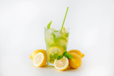 Bir bardak buzlu limonata. Limon dilimleri, nane yaprakları ve beyaz arka planda izole edilmiş buz ile alkolsüz mojito içerken çekilmiş bir stüdyo fotoğrafı. Kapatın, boşluğu kopyalayın..