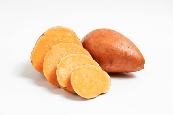 Farm raised organic sweet potato tubers laid in composition on textured background. The edible tuberous root vegetable on table counter. Clean eating concept. Background, close up, flat lay, top view.