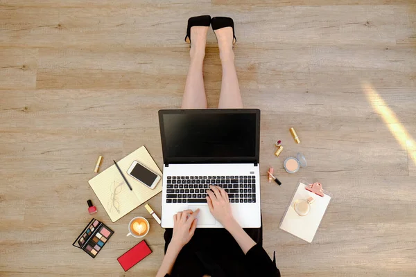 Siyah elbiseli genç bir kadının ahşap zeminde oturup dizüstü bilgisayarı üzerinde çalışmasının en iyi görüntüsü. Dişi ayağının kesilmiş hali. Kapat, kopyala boşluk, arkaplan.