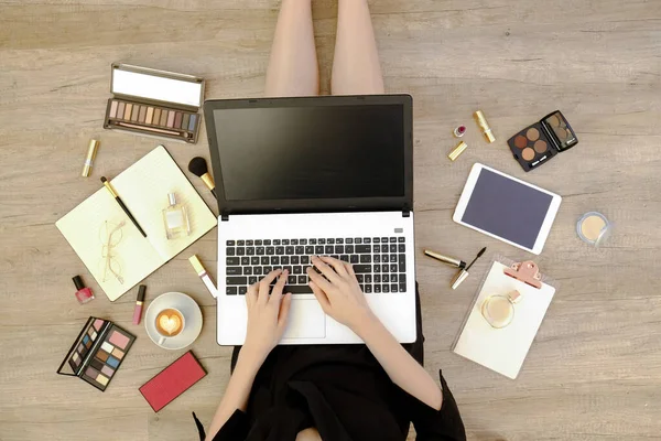 Siyah elbiseli genç bir kadının ahşap zeminde oturup dizüstü bilgisayarı üzerinde çalışmasının en iyi görüntüsü. Dişi ayağının kesilmiş hali. Kapat, kopyala boşluk, arkaplan.