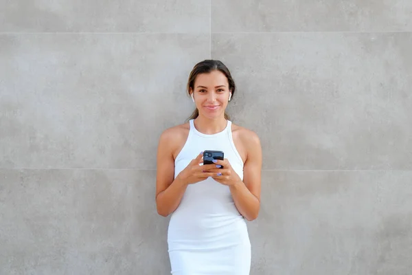 Young beautiful woman of Arabic ethnicity wearing tight white dress standing near the grunged concrete textured wall. Close up, copy space, background.