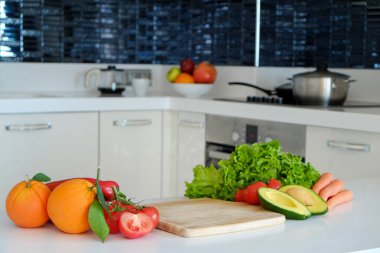Sebze ve sebzeler beyaz tezgahın üzerine serilmişti. Avokado, marul salatası yaprakları, domates ve diğer sebzeler mutfak masasında. Vejetaryen diyeti. Kapat, boşluğu kopyala, arkaplan, üst görünüm.
