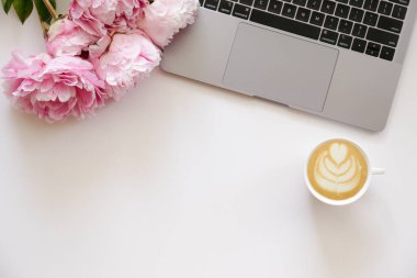 Kırpılmış çekim ya da dizüstü bilgisayar klavyesi, kapuçino ve desenli masa üzerindeki yazı için bir sürü kopya alanı olan şakayık çiçekleri. Kapat, üst görünüm.