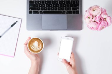 Beyaz dizüstü bilgisayarda çalışan, masa arkası desenli bir kadının en iyi görüntüsü. Çiçek buketli kadınsı çalışma alanı. Kapat, boşluğu kopyala.