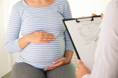 Muayene için doktorun muayenehanesinde hamile bir kadın. Hamileliğin üçüncü üç ayında fiziksel muayenede tanınmayan bir kadının görüntüsü. Kapat, kopyala boşluk, arkaplan.