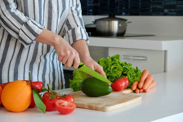 Mutfağında çeşitli meyve, sebze, şifalı ot ve sebze kesen tanınmayan bir kadın resmi var. Profesyonel aşçı malzemeleri dilimliyor. Vegan gıda konsepti. Kapat, kopyala boşluk, arkaplan.
