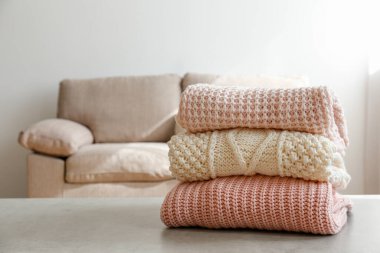 Masada temiz, yeni yıkanmış, düzgünce katlanmış kadın giysileri yığını var. Masada bir yığın gömlek, elbise ve süveter, beton duvar arkaplanı. Boşluğu kopyala, kapat, üst görünüm.