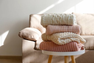 Masada temiz, yeni yıkanmış, düzgünce katlanmış kadın giysileri yığını var. Masada bir yığın gömlek, elbise ve süveter, beton duvar arkaplanı. Boşluğu kopyala, kapat, üst görünüm.