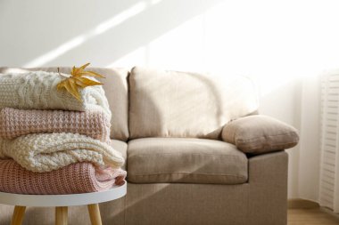 Masada temiz, yeni yıkanmış, düzgünce katlanmış kadın giysileri yığını var. Masada bir yığın gömlek, elbise ve süveter, beton duvar arkaplanı. Boşluğu kopyala, kapat, üst görünüm.