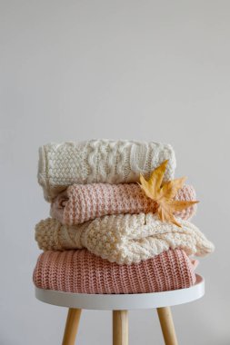 Temiz, yeni yıkanmış kadın kıyafetleri yığını ahşap masanın üzerinde. Masada bir yığın gömlek, elbise ve süveter, beton duvar arkaplanı. Boşluğu kopyala, kapat, üst görünüm.