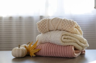 Masada temiz, yeni yıkanmış, düzgünce katlanmış kadın giysileri yığını var. Masada bir yığın gömlek, elbise ve süveter, beton duvar arkaplanı. Boşluğu kopyala, kapat, üst görünüm.