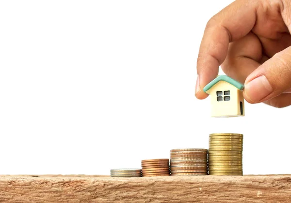 Human hand putting house model on coins stack, saving or investment for a house on white background.