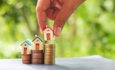 Kadın, ahşap bir ev modelinin elini tutuyor. Yığının üzerine g harfi koyuyor.