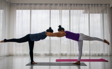 Öğretmen öğrenciye yoga konsepti öğretecek. Orta yaşlı Asyalı bir kadın başka bir kadına yoga yapmayı öğretiyor. Uzatma pozisyonunda, öğretmenin doğru duruşu yakalamak için geldiği yerde..