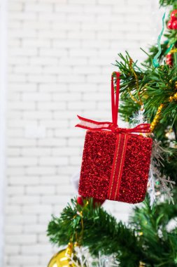 Kırmızı hediye kutusuyla süslenmiş Noel ağacı beyaz bir duvarda, kopyalama alanı.
