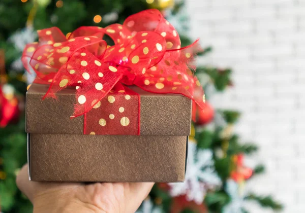 Kırmızı hediye kutusuyla süslenmiş Noel ağacı beyaz bir duvarda, kopyalama alanı.