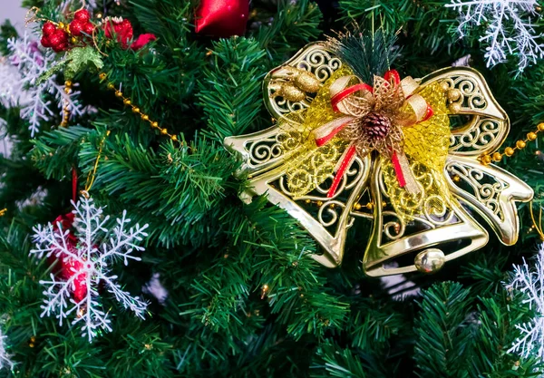 Beyaz bir duvarda altın çan oyuncaklarıyla süslenmiş Noel ağacı, kopyalama alanı.