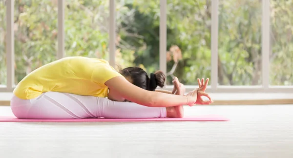 Sarı tişört giyen Asyalı bir yoga öğretmeni vücudunu yogayla güçlü ve sağlıklı olmak için eğitiyor..