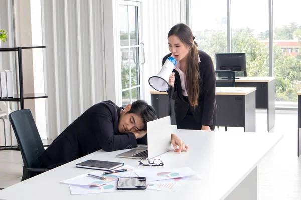 The female secretary holds a megaphone to wake the boss who is tired.