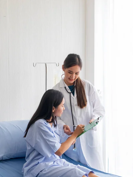 Asyalı bir kadın doktor hastayı odadaki bir yatakta muayene etti..