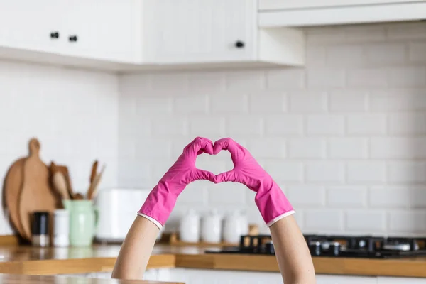 Hart gemaakt van roze beschermende handschoenen op witte keuken achtergrond... Vrouw handen dragen beschermende handschoenen. Concept van schone keuken, succesvolle duim ja ok teken — Stockfoto