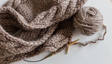 Bej renkli yün örgü ve örgü iğneleri Beyaz ahşap zemin üzerinde. Bir hobi olarak örgü. Aksesuar örme için.