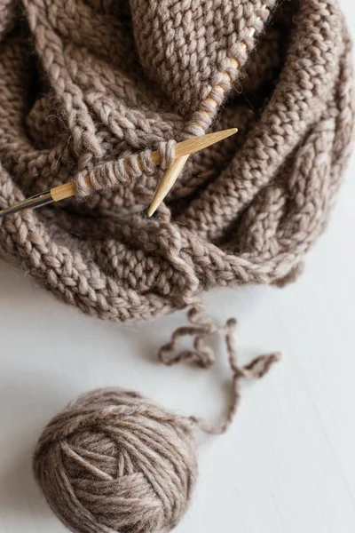 Beige knitting wool and knitting needles on white wooden background. Knitting as a hobby. Accessories for knitting.