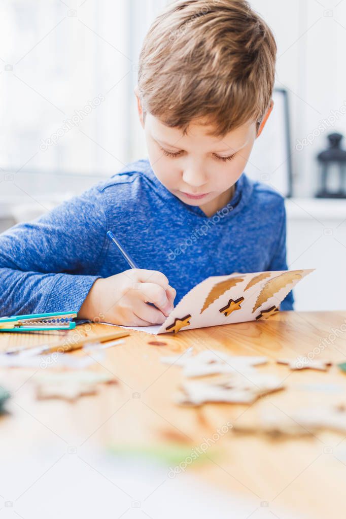 Nine years boy preparing christmas greeting cards for grandparents. Handmade Christmas gift ideas