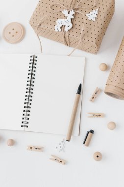 Açık defter, kalem, kağıt, Hediyelik etiket, ahşap boncuk dokulu beyaz arka plan üzerinde kaydırma sarılı el sanatları Hediyelik. Modern Noel düz yatıyordu. İyi Bayramlar