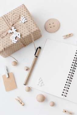 Açık defter, kalem, kağıt, Hediyelik etiket, ahşap boncuk dokulu beyaz arka plan üzerinde kaydırma sarılı el sanatları Hediyelik. Modern Noel düz yatıyordu. İyi Bayramlar