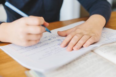 Liseli evde masa üzerinde Ukrayna dilde matematik ödevini yapıyor. Çocuk sayıları bir sütuna bölün. Evde eğitim kavramı