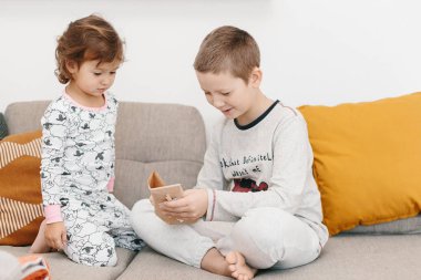 Oturma odasında kanepede oturan advent takvimi hediye açılış pijama giymiş kardeş