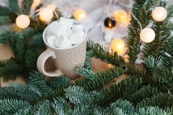 Spruce branches in basket and cup with cacao and marshmallow. Rustic new year christmas decoration at home, scandinavian interior
